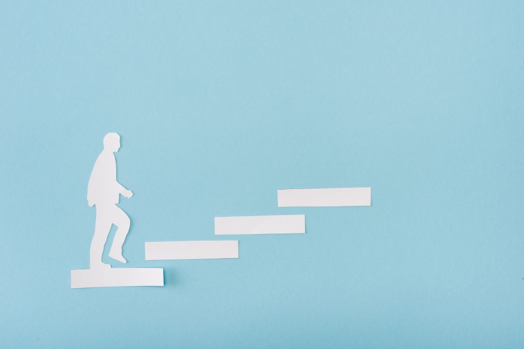 Top view of paper man on career ladder on blue